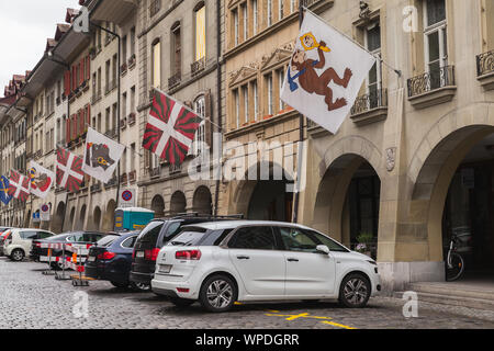 Bern, Switzerland - May 7, 2017: Street view of Kramgasse or Grocers Alley. Cars are parked under colorful flags of Swiss cantons Stock Photo