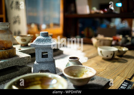 Taipei, Taiwan: Wooden table at traditional tea house in Jiufen, Taiwan. Laid with beautiful handmade, ceramic tea cups with blurry background Stock Photo
