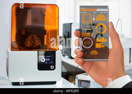 Hand with futuristic transparent smartphone. Application for control 3D printer in the laboratory. Stock Photo