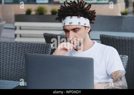 Thoughtful freelancer it developer thinking about fixing software bugs on laptop. Focused student watching tutorial on e-learning website platform, le Stock Photo