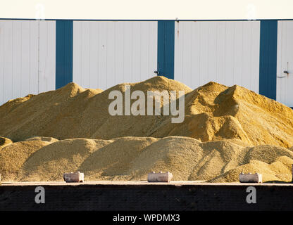 Huge sand and gravel pile in front of warehouse Stock Photo