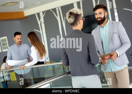 Business people discussing over documents in office lobby. Stock Photo