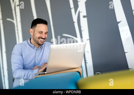 Smiling male blogger keyboarding article in electronic newspaper using laptop Stock Photo