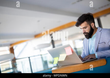 Smiling male blogger keyboarding article in electronic newspaper using laptop Stock Photo