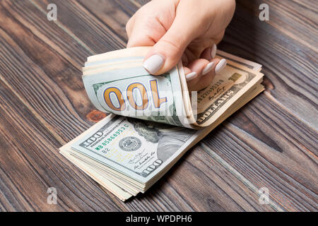 Perspective view of female hands counting money. One hundred dollar banknotes on wooden background. Salary concept. Bribe concept. Stock Photo