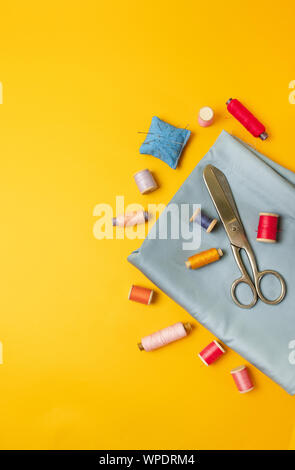 Sewing accessories on a colored yellow background top view. Stock Photo