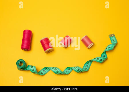 Composition with threads and sewing accessories and tape measure on color background, flat lay Stock Photo