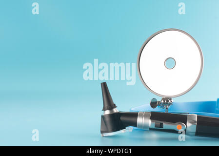 Otoscope with reflector mirror on blue background in health care concept. Stock Photo