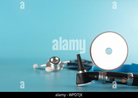 Otoscope with stethoscope and reflector mirror on blue background. Stock Photo