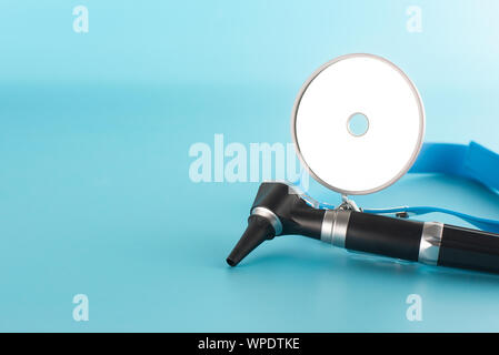 Otoscope with reflector mirror on blue background in health care concept. Stock Photo