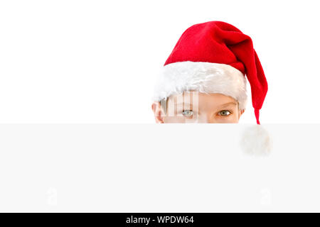 Young boy in red Santa hat hiding behind a blank paper Stock Photo