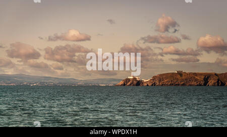 Howth Lighthouse at the entrance to Dublin Bay located at rocks of Howth Head with Dublin city on background. Irish sea. Stock Photo