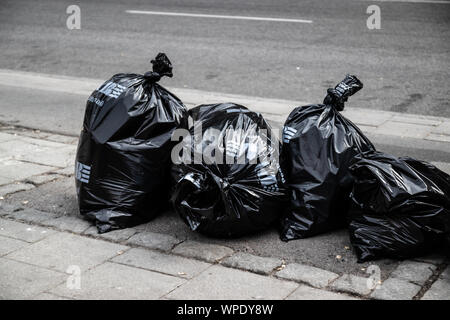 Caring for ecology concept. Garbage sorting. Pile of black garbage on the footpath at side road in big city, pollution trash Stock Photo