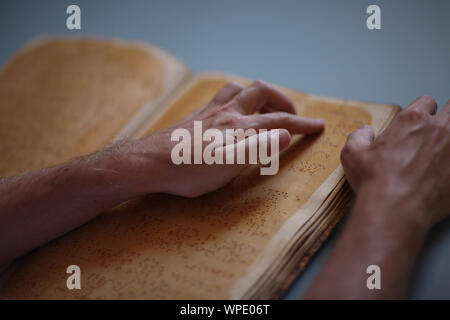 The hands of a blind man reading a book with a special Braille Stock Photo