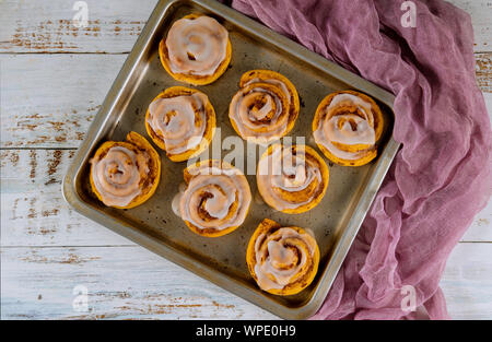 Homemade cinnamon rolls in baking pan on white wooden table. Stock Photo