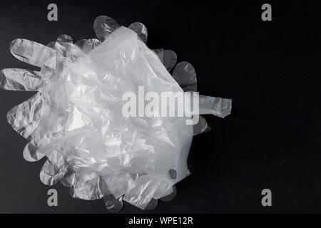 Plastic bag with handles, gloves, on a black background . Used plastic bag for recycling. Concept - ecology, planet pollution with plastic cellophane Stock Photo