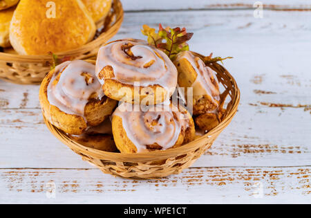 Cinnamon rolls with glaze on the top in wooden plate. Stock Photo