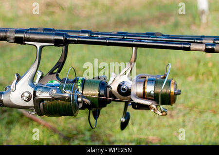 Closeup of a reel fishing rod on a prop in the background a lake and  mountains Stock Photo - Alamy