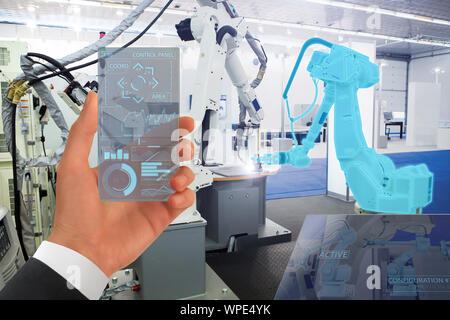 Engineer uses a futuristic transparent smartphone to control robotic arm. Smart industry 4.0 concept. Stock Photo