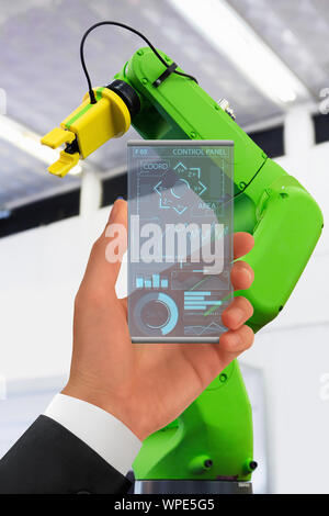 Engineer uses a futuristic transparent smartphone to control robotic arm. Smart industry 4.0 concept. Stock Photo