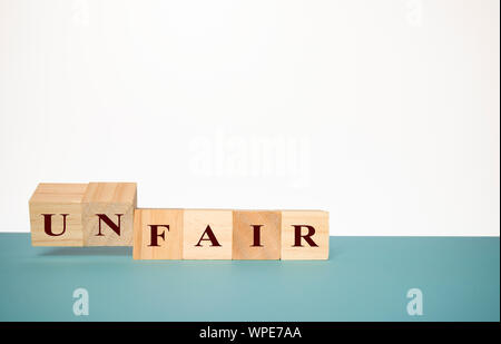Flipping two wooden cube to change the word Unfair to fair on neutral background Stock Photo