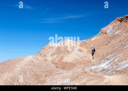 Young casual man with backpack on the path at moon like landscape of Valle de la Luna (Moon valley), Chile. Travel Lifestyle hiking concept summer vac Stock Photo