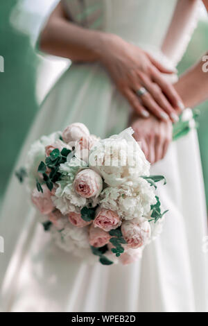 close up. the bride holds the wedding bouquet behind her back. Stock Photo