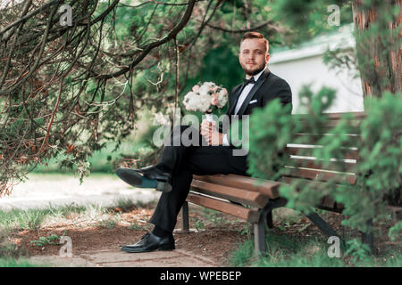 groom is waiting for the bride sitting sitting on the bench. Stock Photo