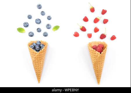 Waffle i cones. Creative concept photo of waffle cones filled with fresh summer strawberries and blueberries.Berries fall out from a waffle cones. Stock Photo