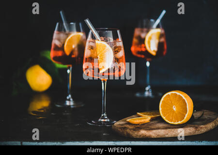 Aperol Spritz aperitif with oranges and ice in glass with eco-friendly glass straw on concrete table, black background, selective focus. Summer refres Stock Photo