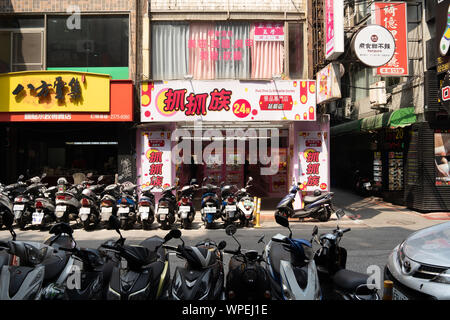 Densely parked scooters on a street in Taipei City, enclosing the street. A common sight in Taiwan. Stock Photo