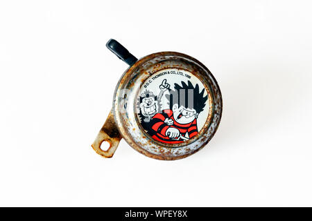An old and rusty 'Dennis the Menace and Gnasher' (characters from the Beano children's comic) bicycle bell, isolated on a white background Stock Photo