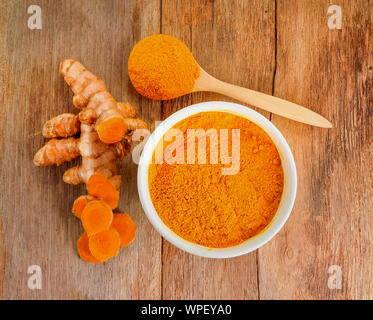 top view Turmeric roots with turmeric powder on wooden background Stock Photo