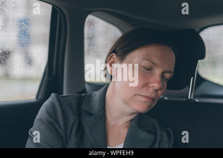 Tired businesswoman sleeping at car back seat, exhausted female executive fallen asleep in corporate limousine