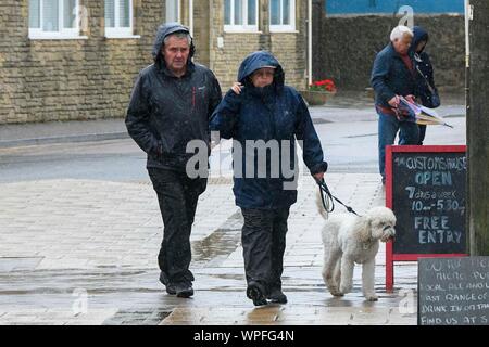 West Bay, Dorset, UK.  9th September 2019. UK Weather.  A couple walking their dog on a day of heavy rain at the seasde resort of West Bay in Dorset.  Picture Credit: Graham Hunt/Alamy Live News Stock Photo