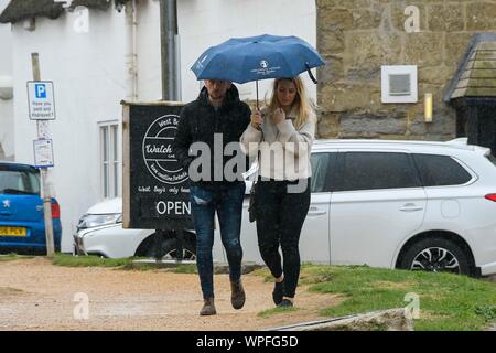 West Bay, Dorset, UK.  9th September 2019. UK Weather.  A couple walking with an umbrella up on a day of heavy rain at the seasde resort of West Bay in Dorset.  Picture Credit: Graham Hunt/Alamy Live News Stock Photo