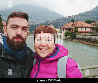 Smiling millennial couple taking selfie scenic Italian mountains against. Real people vacation lifestyle Stock Photo