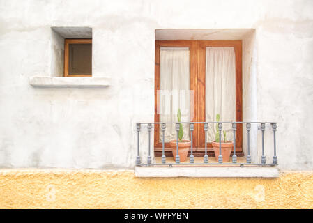 Typical Andalusian street background in Spain with a balcony decorated with flowerpots and geraniums. Empty copy space for Editor's text. Stock Photo