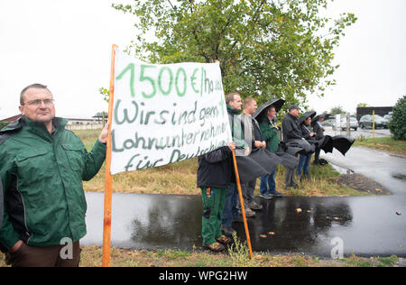 09 September 2019, Brandenburg, Nauen Ot Ribbeck: Before the visit of the Minister of Agriculture and the Minister of the Environment, demonstrators from the Farmers' Union wait at the entrance to the Havellandhof Ribbeck farm with the banner 'We like to be contractors for Germany'. The farm is one of ten demonstration farms of the F.R.A.N.Z. project (For resources, agriculture and nature conservation with a future). The project aims to demonstrate that agriculture is compatible with biodiversity conservation. Under the motto 'Together for more diversity in the agricultural landscape', ten dem Stock Photo