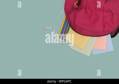 school bag with book and color pencil isolated on green background, back to school concept. Stock Photo