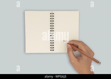 Top view- two hands hold a empty book spread and writing a notebook. Stock Photo
