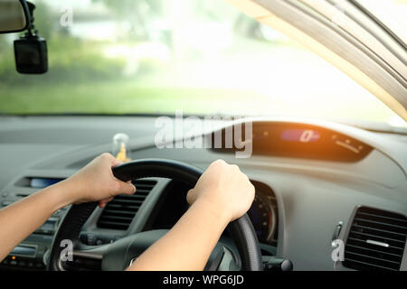 The hands are holding the steering wheel and driving on a light day. Stock Photo