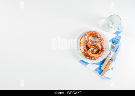 Oktoberfest festive cutlery set  with with a traditional checkered  tablecloth, plate, pretzel, fork, knife and a glass of beer. background for Restor Stock Photo