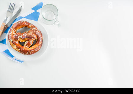 Oktoberfest festive cutlery set  with with a traditional checkered  tablecloth, plate, pretzel, fork, knife and a glass of beer. background for Restor Stock Photo