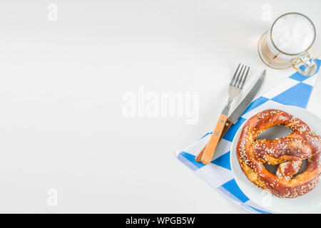 Oktoberfest festive cutlery set  with with a traditional checkered  tablecloth, plate, pretzel, fork, knife and a glass of beer. background for Restor Stock Photo