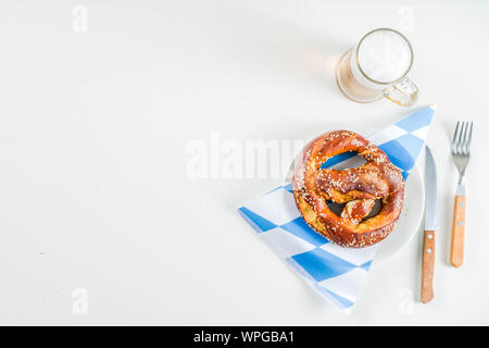 Oktoberfest festive cutlery set  with with a traditional checkered  tablecloth, plate, pretzel, fork, knife and a glass of beer. background for Restor Stock Photo