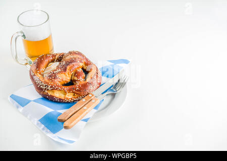 Oktoberfest festive cutlery set  with with a traditional checkered  tablecloth, plate, pretzel, fork, knife and a glass of beer. background for Restor Stock Photo