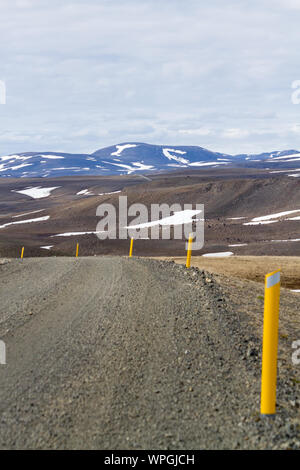 Gravel road with yellow markings leading through a desert-like lava landscape; Iceland. Stock Photo