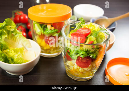 Salad jars wiht green leaves, tomatoes and vegetables. Stock Photo