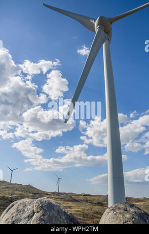 View of a wind turbines on top of mountains, blue cloudy sky as background in Portugal Stock Photo